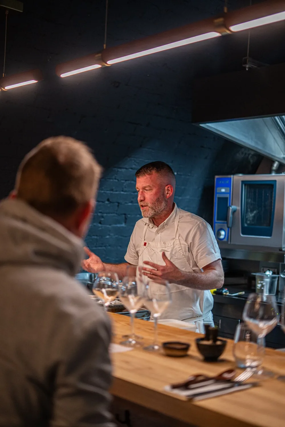 A member of staff talking to a guest across the counter of an open kitchen