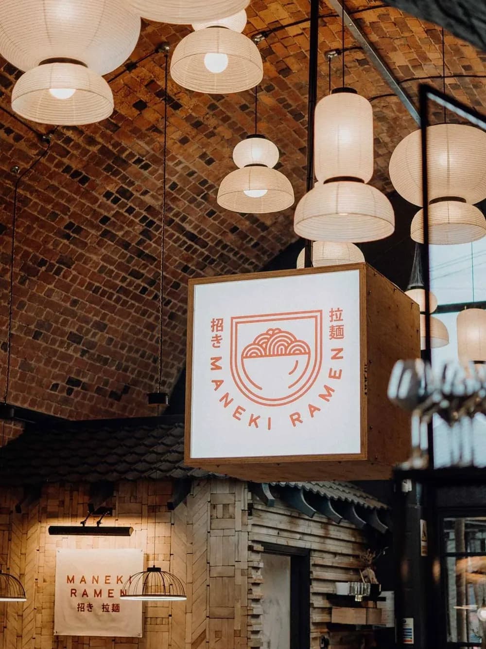 The illuminated Maneki Ramen sign above a lantern-lit entrance