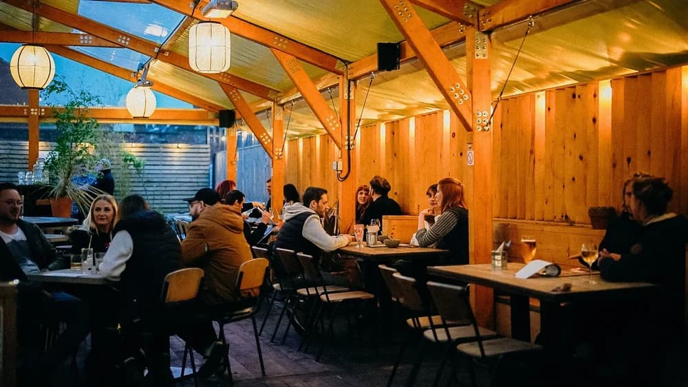 A busy timber-framed dining room with guests seated at long tables
