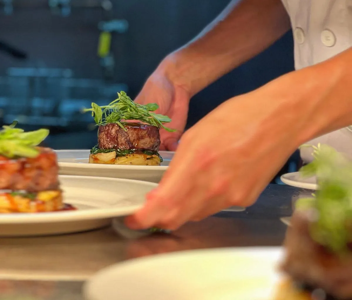 A chef finishing a plated dish at the pass